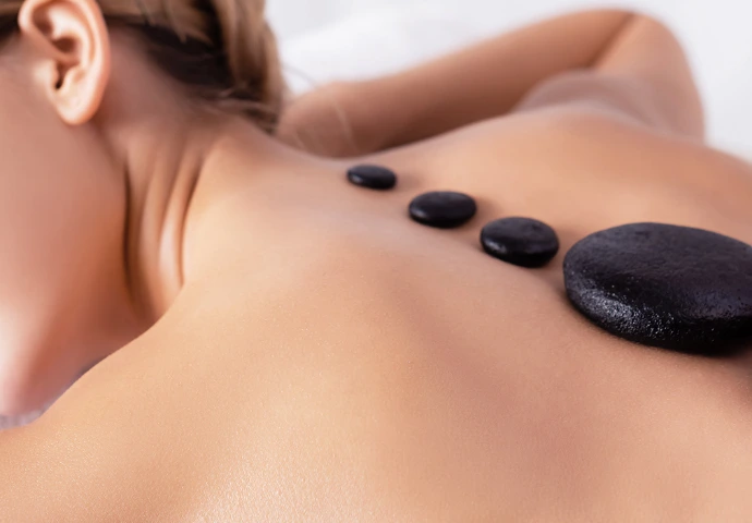 Pierres chaudes de massage alignées sur la colonne d'une femme allongée sur le ventre